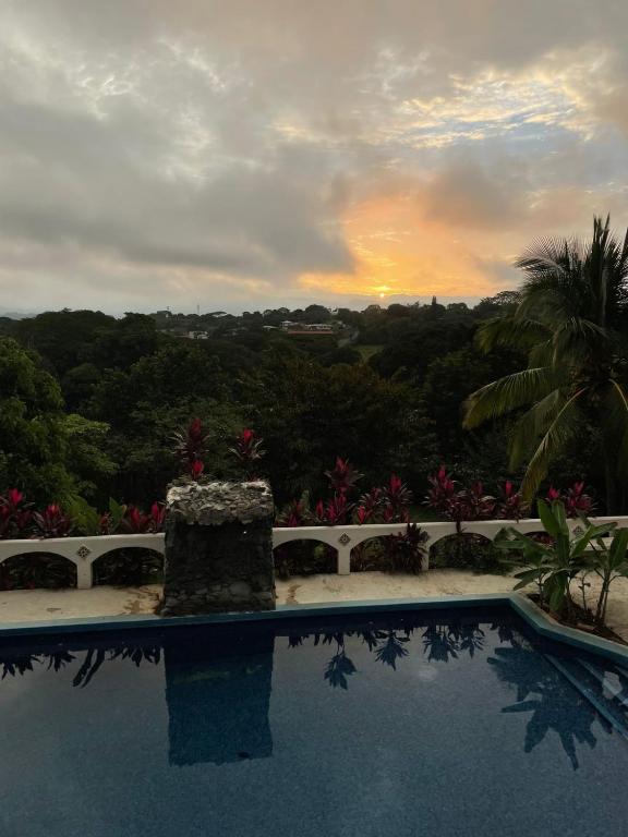 a swimming pool with a sunset in the background at Casa Eliza in Alajuela