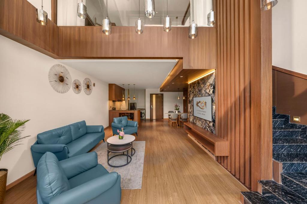 A polished lounge with blue seating, a television wall and a staircase.