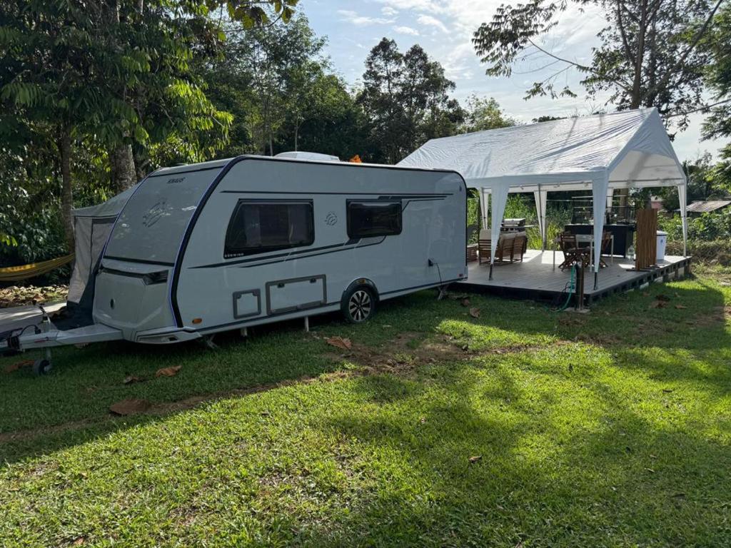a white caravan with a tent in a field at Canopy Villa Nuang Hill in Bentong