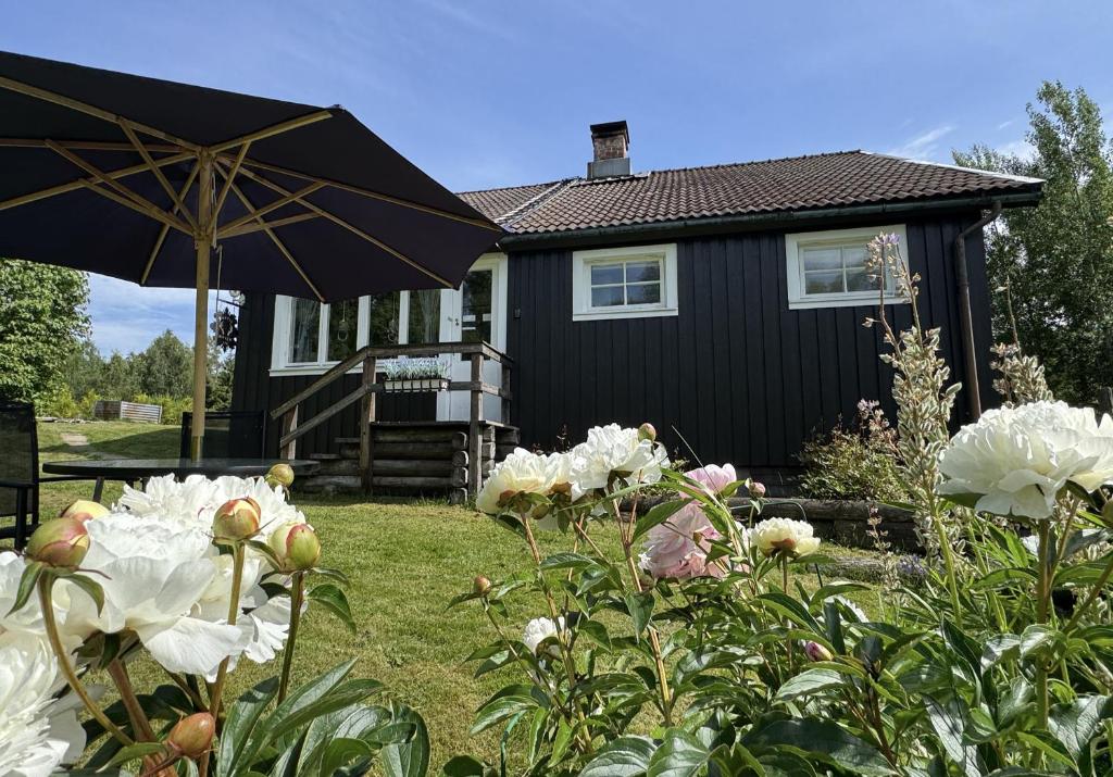 a black house with an umbrella and some flowers at Rustic Haven Bed and Breakfast -Entire Private Apartment 2km from Klarälvsbanan and Swimming area in Munkfors