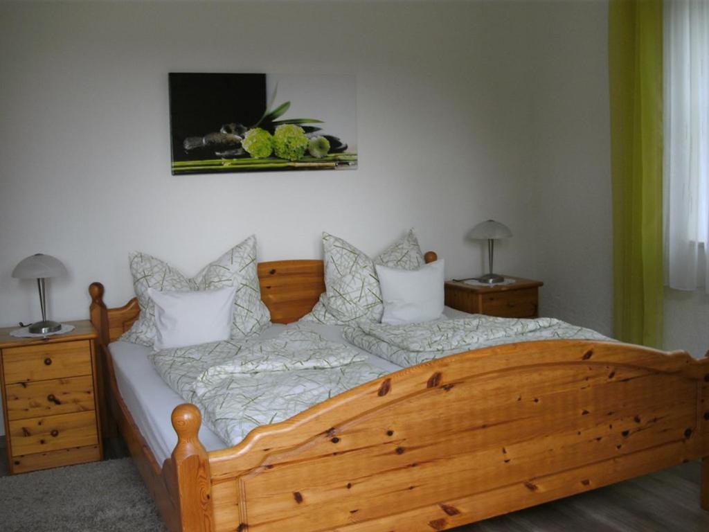 1 dormitorio con cama de madera, 2 mesitas de noche y TV en Ferienwohnungen Malz, en Blaibach
