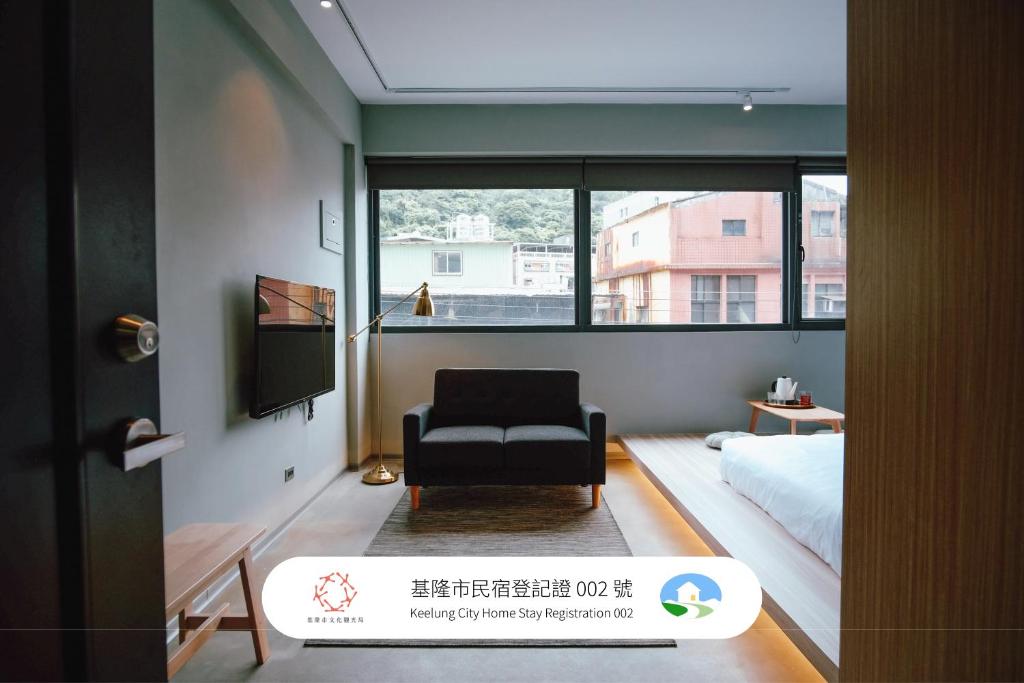 a room with a chair and a bed and a window at Spangle Inn in Keelung