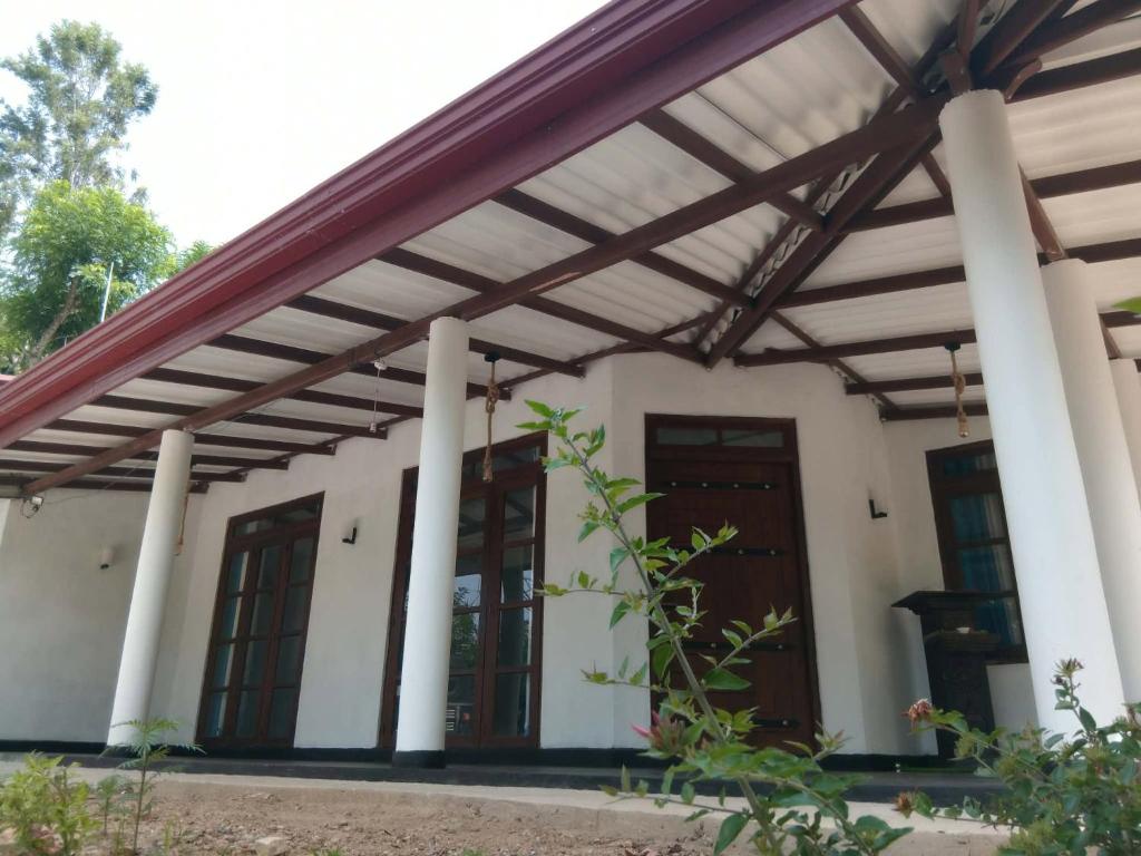 a house with awning and columns and a porch at NIVRA Homestay in Kumbalwela