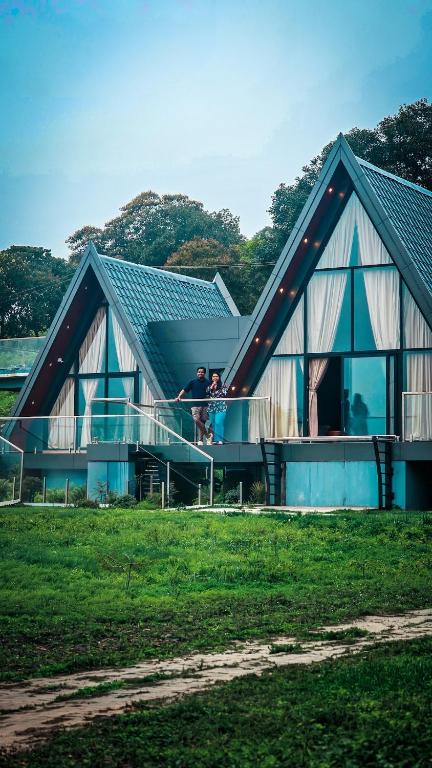 two people standing on the balcony of a house at Indian Bungalows in Vagamon