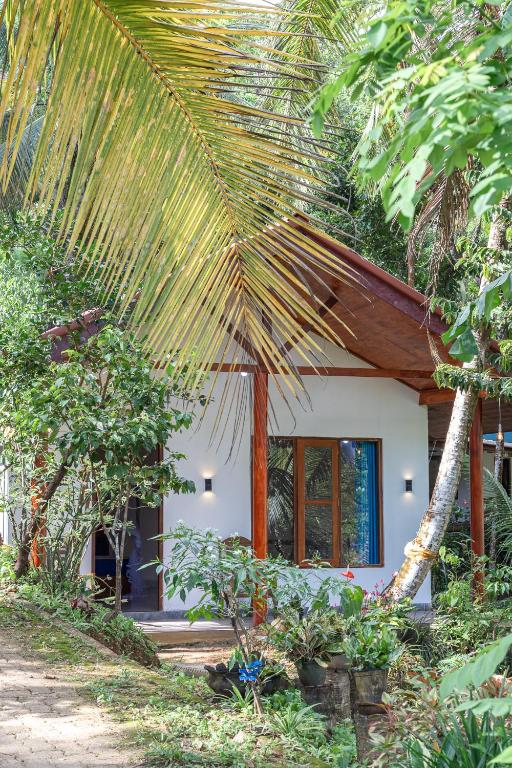 a house with a large palm tree in front of it at Rainforest Soul Villa in Mederipitiya