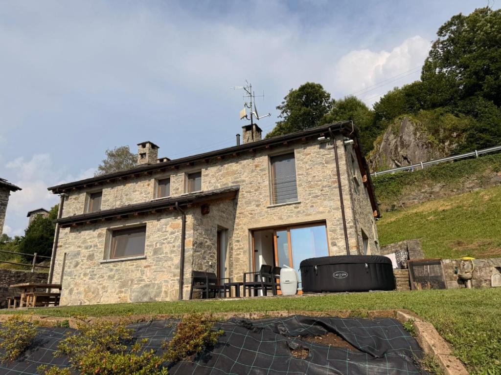 a stone house on a hill with a yard at Arzo Mountain Chalet in Morbegno