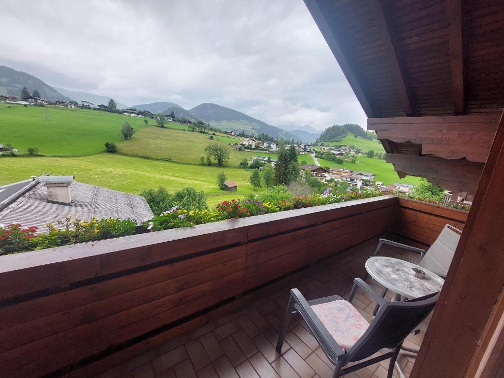a balcony with two chairs and a table and a field at Alpen Appartements in Embach