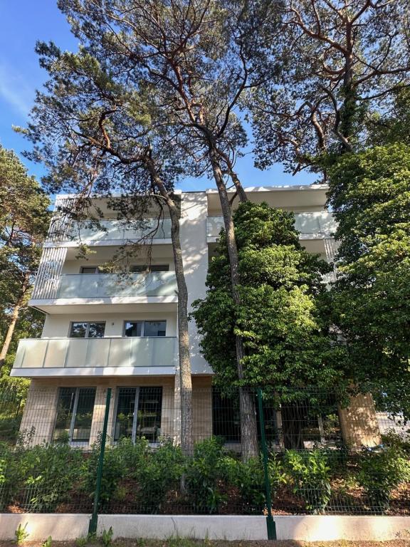 a white building with trees in front of it at Apartamenty MAREA in Jurata