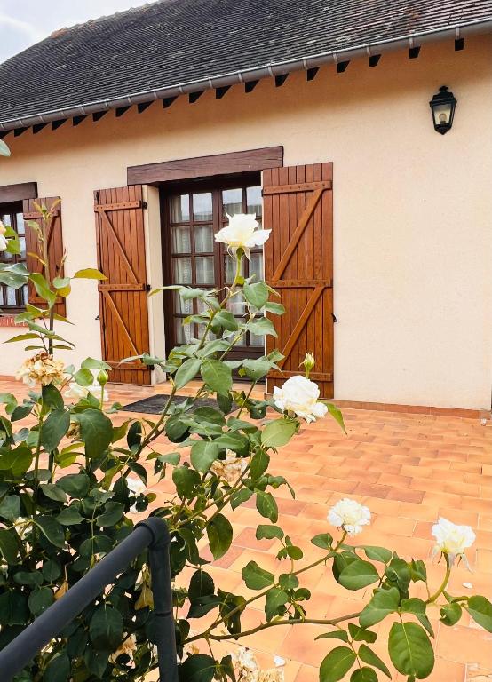 a house with wooden doors and a plant with white flowers at Le Clos Colette in Neuvy