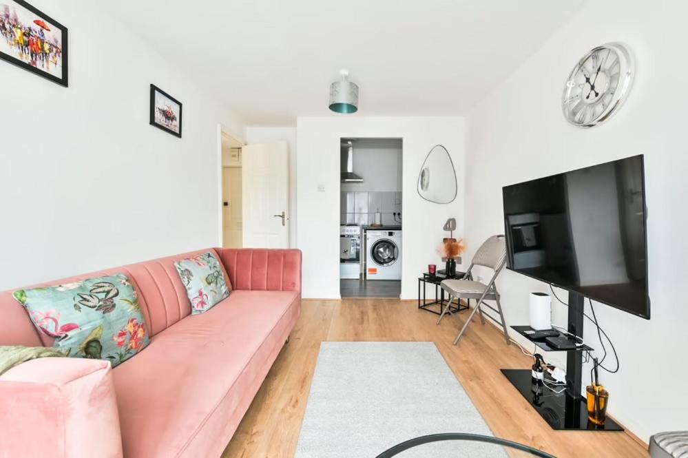 a living room with a pink couch and a flat screen tv at Paprika Nest in Hendon
