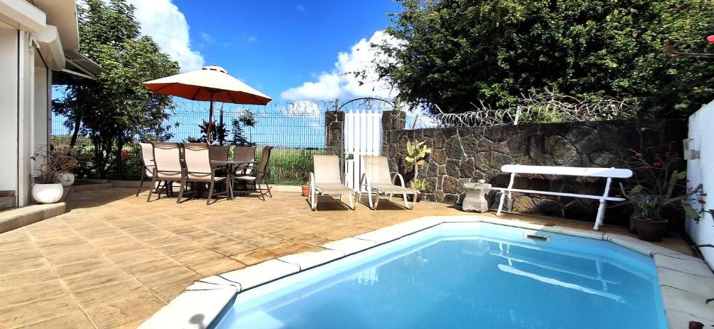 a swimming pool with a table and chairs and an umbrella at Bay Rose in Pointe d'Esny