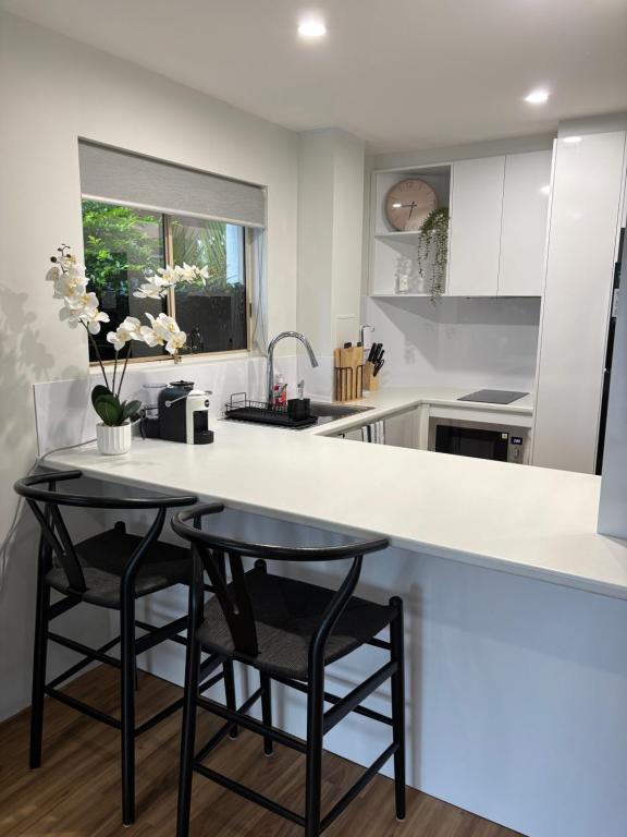 a kitchen with a white counter and two stools at Surfers 641 in Gold Coast
