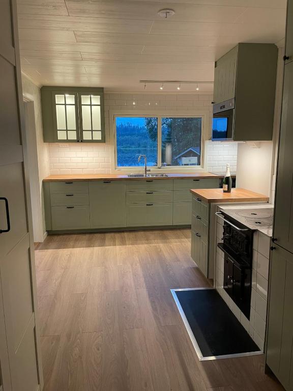 a large kitchen with green cabinets and a sink at Idyllic cottage with lake view with 11 beds in Ludvika