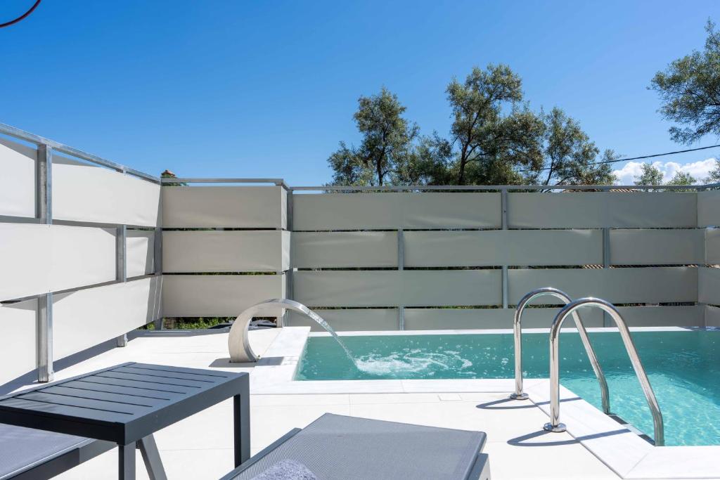 a swimming pool with a table and a bench on a patio at Aurea Ionian Villas in Apolpaina