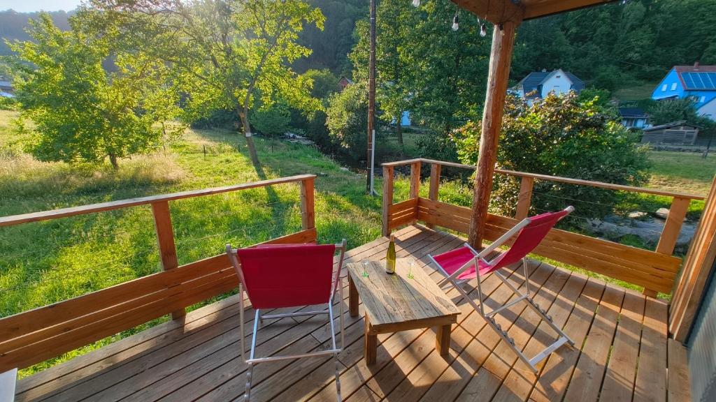 two chairs and a wooden table on a porch at Lodge de la WEISS in Lapoutroie