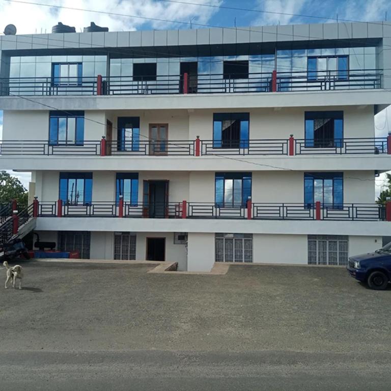 a building with a car parked in front of it at Vibgyor Hotel in Cherrapunji