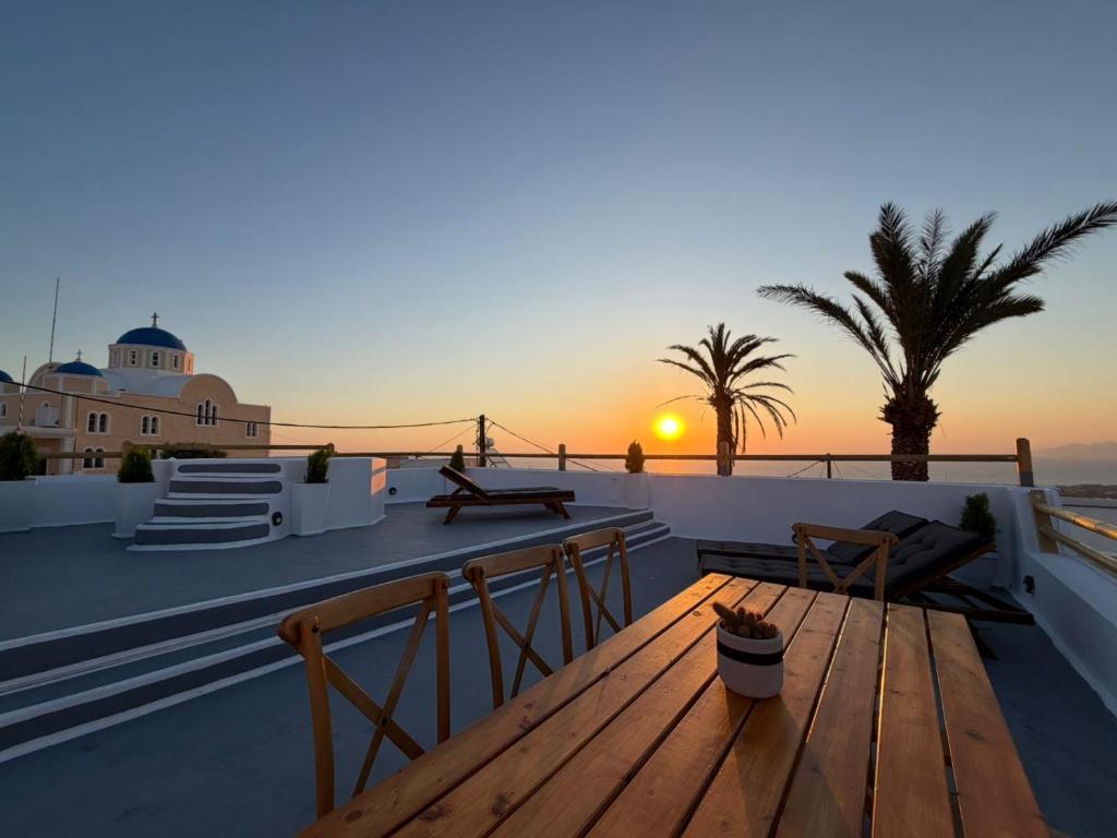 a sunset on the roof of a house with a wooden bench at Dimael Mansion in Fira