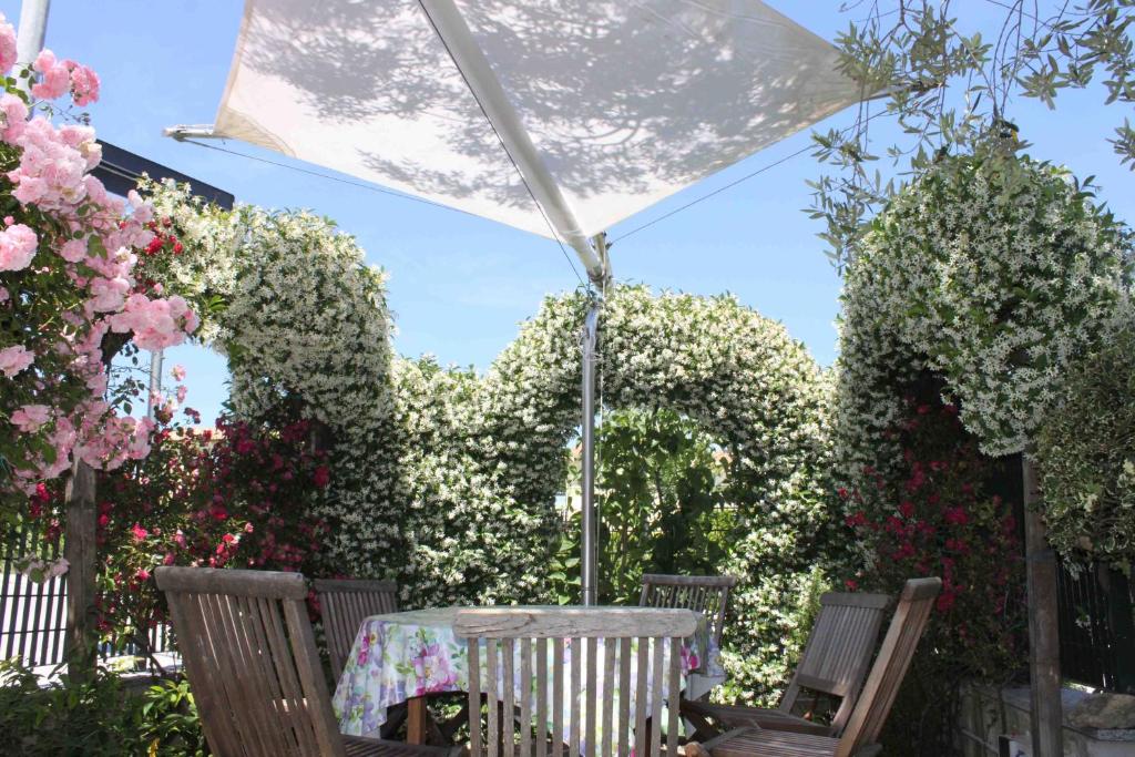 a table and chairs under an umbrella with flowers at Appartamento Stella Marina in Marcelli