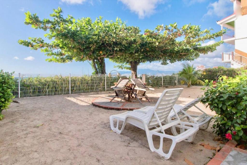 two white chairs and a table and a tree at Villa bougainvillier in Les Trois-Îlets