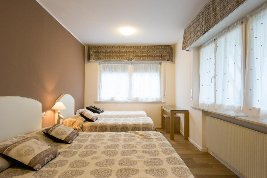 two beds in a room with two windows at Apartments da Edvige in Tarvisio