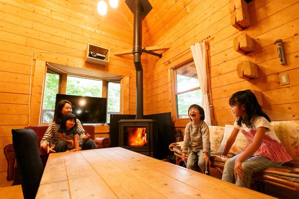 a group of people sitting around a table in a room with a fireplace at ログハウス那須ハイグランド in Nasu
