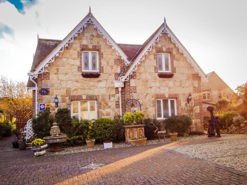 Ein Mann steht vor einem Steinhaus in der Unterkunft Koala Cottage in Ventnor