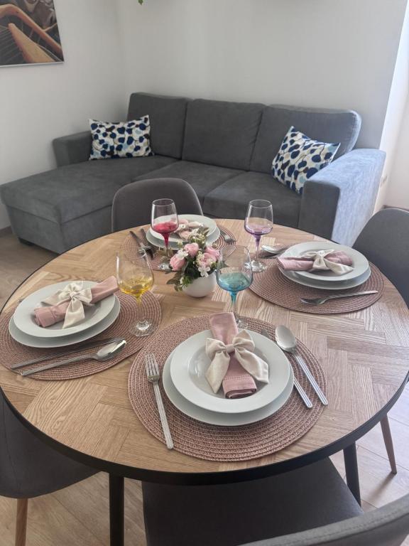 a wooden table with plates and wine glasses on it at Six Apartman in Bükfürdő