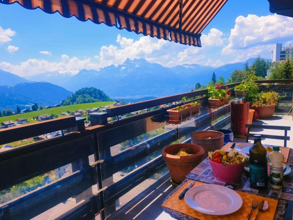 a table on a balcony with a view of mountains at Le Nid d'aigle apt 405 Leysin centre avec forfait piscine sauna jacuzzi en option in Leysin