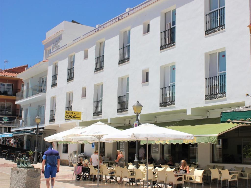 a large white building with tables and umbrellas in front of it at Hotel Cabello in Torremolinos