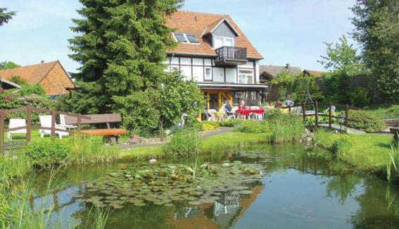 ein Haus mit einem Teich mit Lilien davor in der Unterkunft Hotel Auf Dem Langenhof Wunstorf in Wunstorf