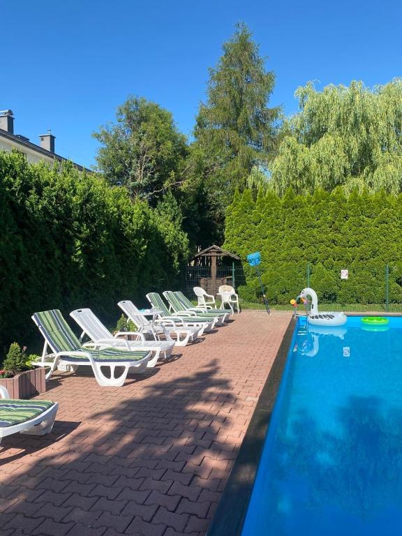 a row of lounge chairs next to a swimming pool at Dom lub apartamenty z widokiem na góry Wichrowe Wzgórza z basenem Brenna in Ustroń