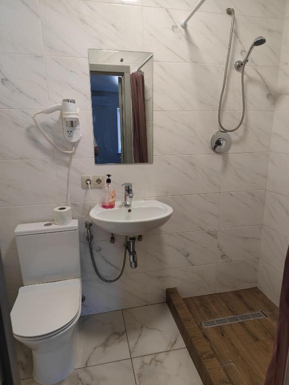 a bathroom with a toilet and a sink and a shower at Zarvanska str apartment in Kamianets-Podilskyi