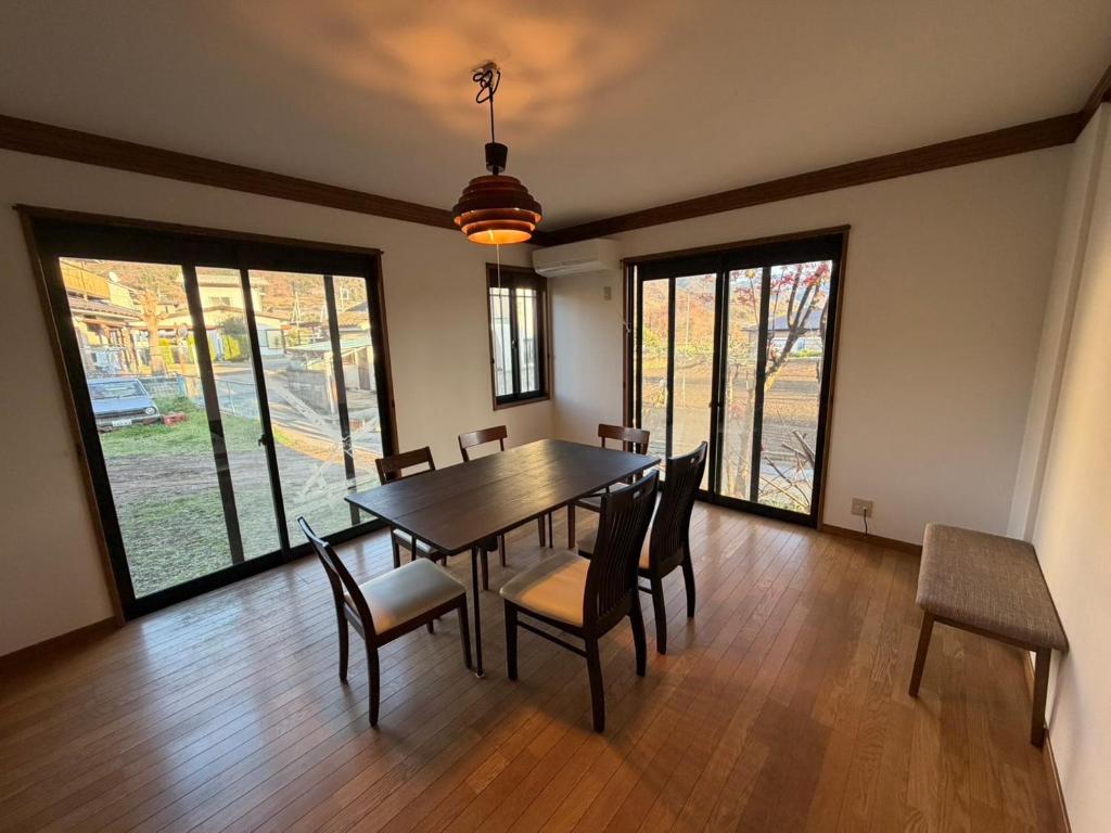 a dining room with a table and chairs and windows at ENZAN STAYS Yamanashi in Enzan