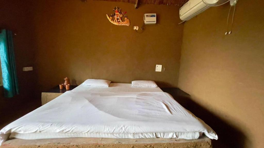 a bedroom with a large bed with white sheets at Rupani Dhani Farm Stay in Gurgaon