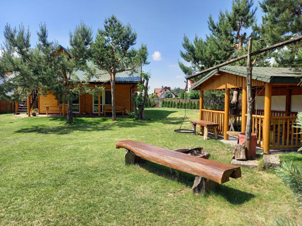 a park with a wooden bench in the grass at Pod lasem dom letniskowy in Majdan Sopocki