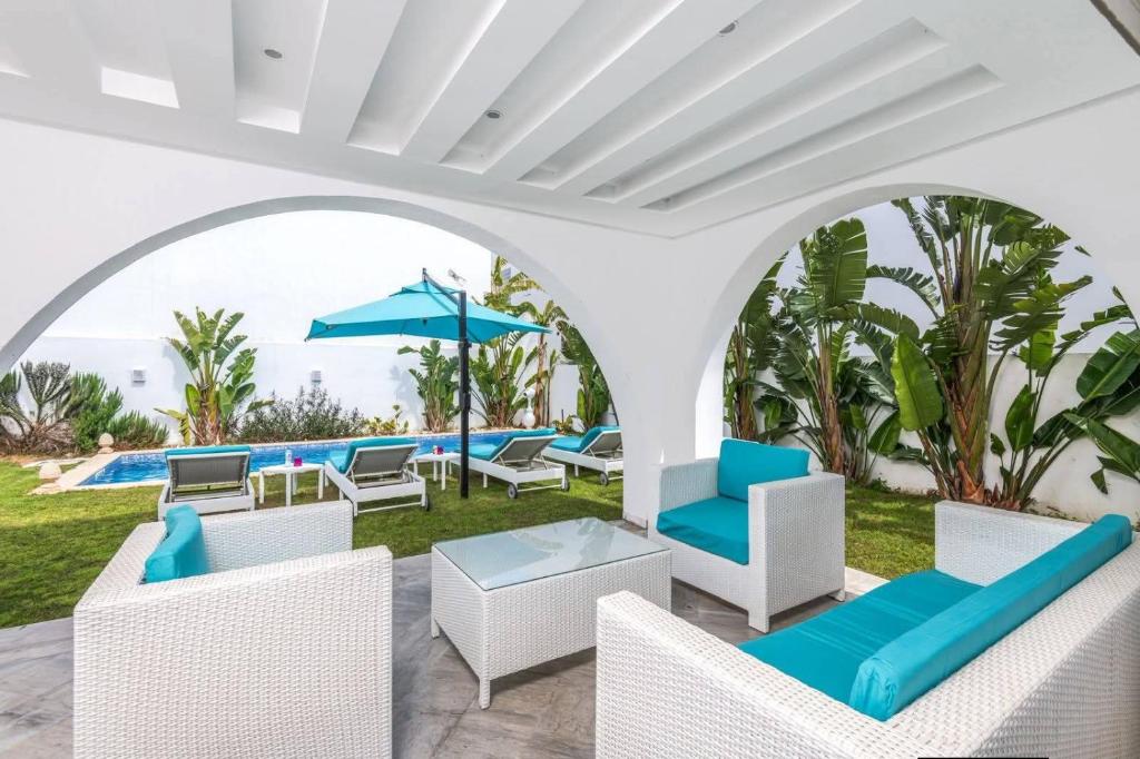 a patio with chairs and an umbrella and a pool at Villa Sky in Bin Rhilouf