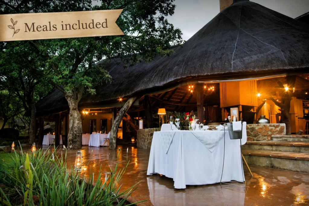 a restaurant with white tables in front of a building at Itaga Luxury Private Game Lodge in Warmbaths