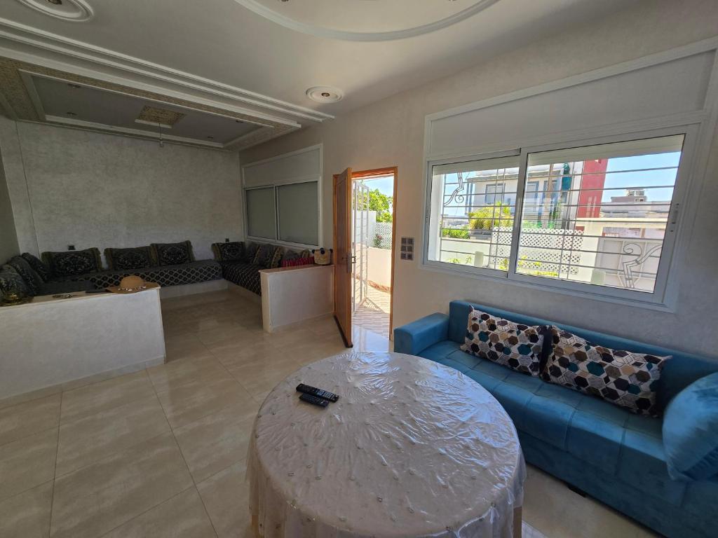 a living room with a blue couch and a table at Villa Sabrina in Moulay Bousselham