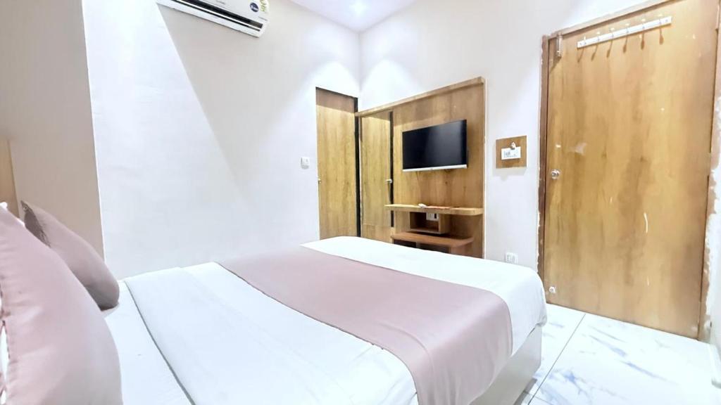 a white bedroom with a bed and a tv at Hotel Planet villa in Ahmedabad