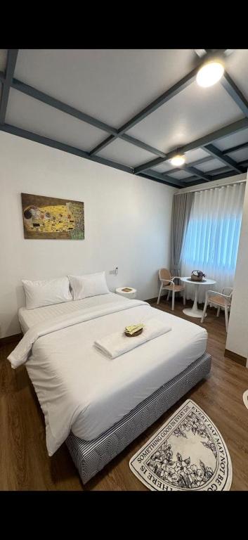 a bedroom with a large white bed and a table at Malina Guesthouse in Ko Phangan