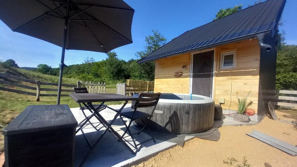a table and chairs and an umbrella in front of a cabin at Marin konak in Gornji Milanovac