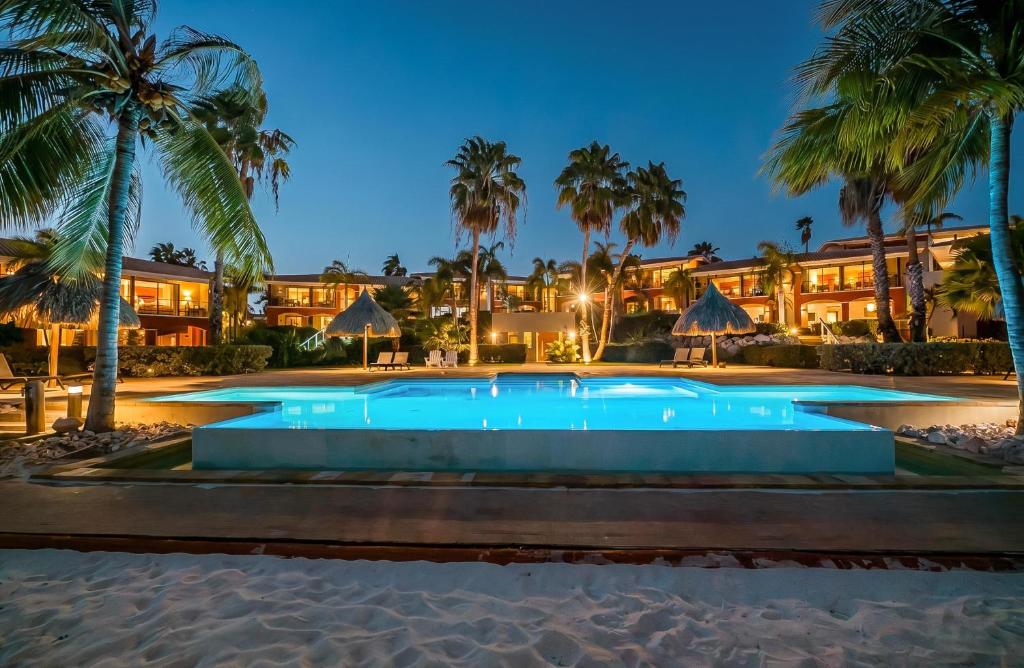 a resort pool with palm trees and a building at Luxury Ocean View Apartment, Private Beach, Infinity Pool, near Jan Thiel C4 in Willemstad