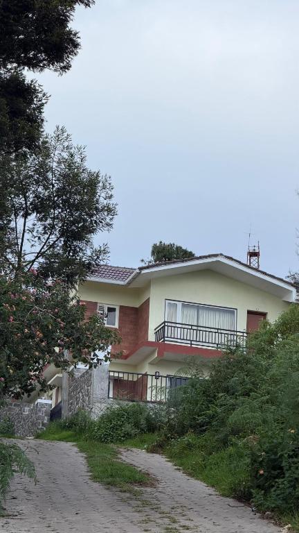 a house with a balcony on the side of a road at Elysian Villa by Hostel Jerusalem in Kodaikānāl