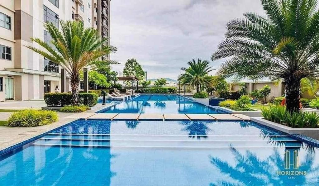 a large swimming pool with palm trees and buildings at Horizons 101 in Cebu City