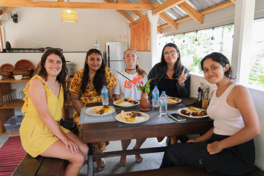 a group of people sitting around a table eating food at Cloud Trails Hostel Ella in Ella
