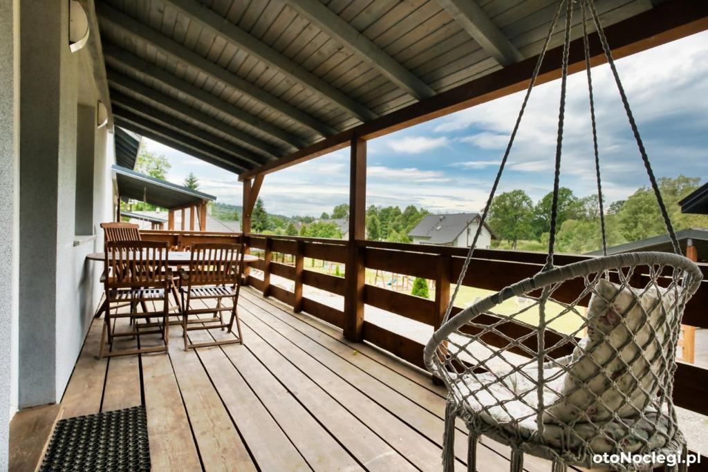 a porch with a swing and a table and chairs at Domki przy Skarpie in Lądek-Zdrój