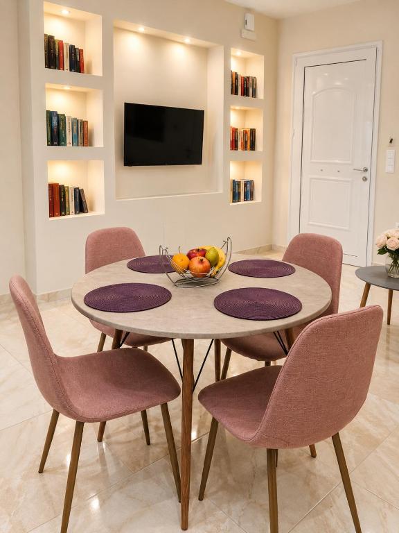 a dining room with a table and chairs and a television at Ma Maison Rose in Kremasti