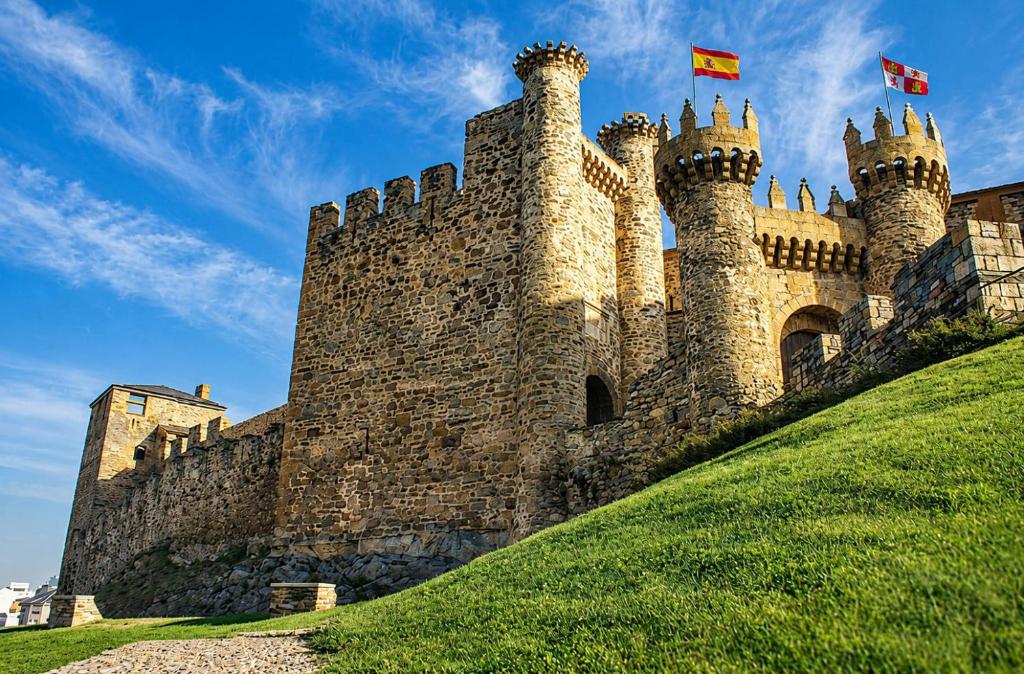 a castle with two flags on top of a hill at Castillo Buenavista in Ponferrada