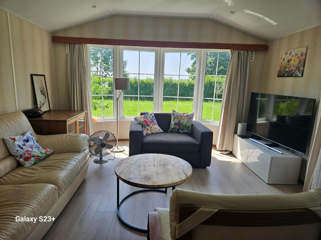 a living room with couches and a flat screen tv at De Weerribben Wieden, Natuurhuisje in Wanneperveen