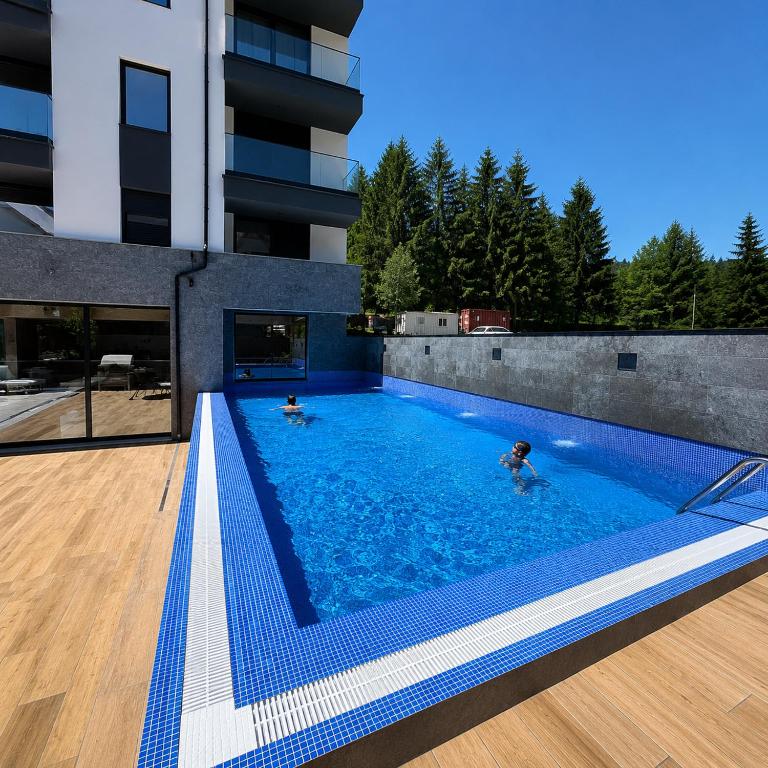 two people swimming in a swimming pool in a building at Hedonist Wellness & Spa in Zlatibor